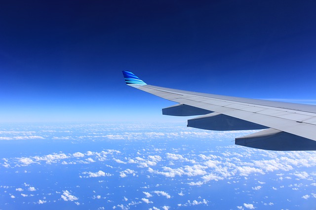 Imagem da asa de um avião em alto céu.